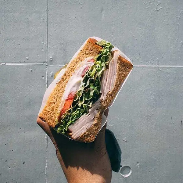 Hand holding deli sandwich