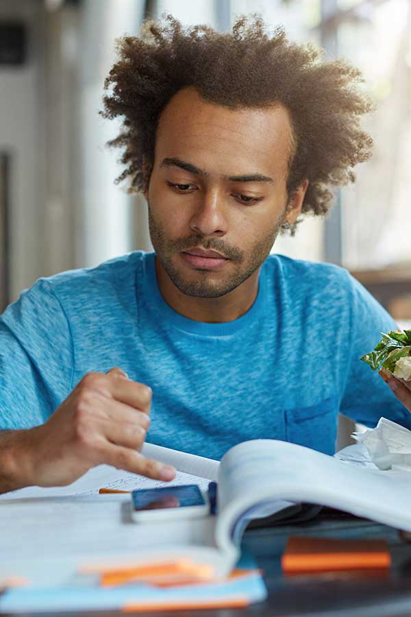 Student looking at phone while eating sandwich